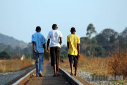 Young men walking along a railway line